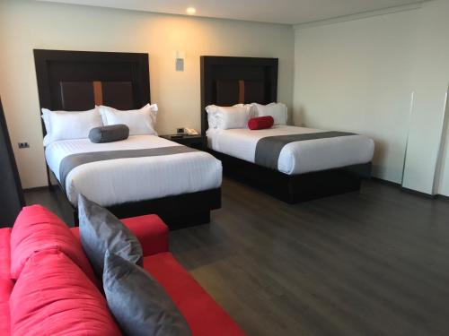 a hotel room with two beds and a couch at Best Western Plus Metepec & Suites in Toluca