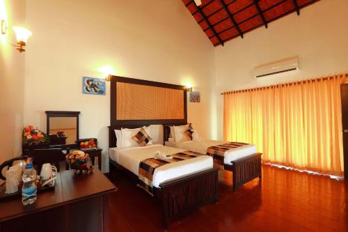 a bedroom with two beds and a table and a desk at Nihara Resort and Spa Cochin in Cochin