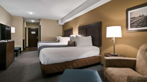 LacombeにあるBest Western Plus Lacombe Inn and Suitesのベッド2台とソファが備わるホテルルームです。