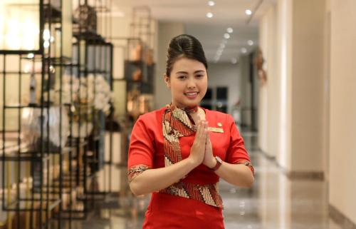 a woman in a red shirt doing a blessing gesture at Swiss-Belinn Airport Surabaya in Sidoarjo