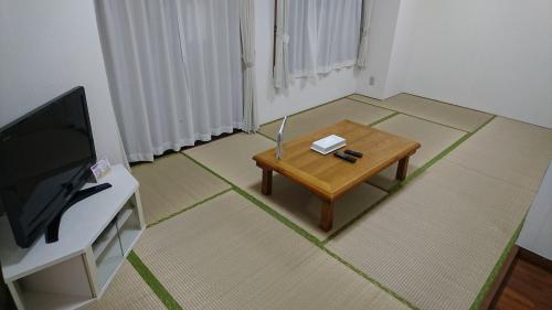 a living room with a coffee table and a television at Kokusai Towns Inn in Naha