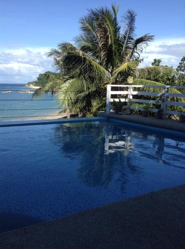 einen Pool mit einem weißen Zaun und dem Meer in der Unterkunft Playa Blanca Beach Resort in Puerto Galera