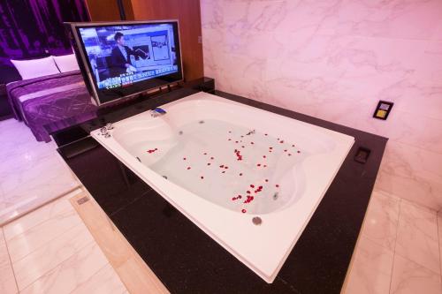 a bath tub with a television in a room at 富士都商務汽車會館 台南市旅館308號 in Tainan