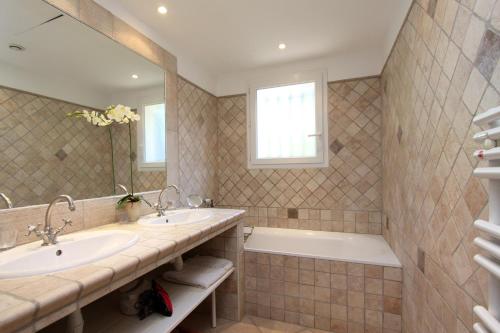 a bathroom with two sinks and a tub and a mirror at Villas les Residences de Scaglione in Porticcio