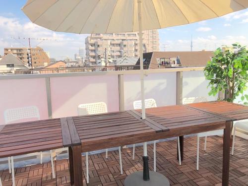 a wooden table and an umbrella on a balcony at Tokyo Art House in Tokyo