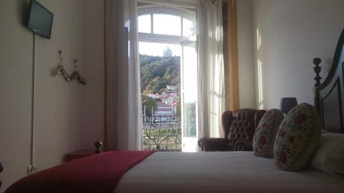 a bedroom with a bed and a large window at A Vianesa - Guest House in Viana do Castelo