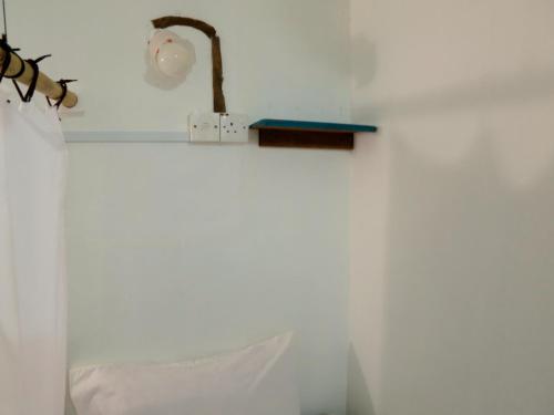 a white wall with a lamp and a white pillow at Pangkor Guesthouse SPK in Pangkor