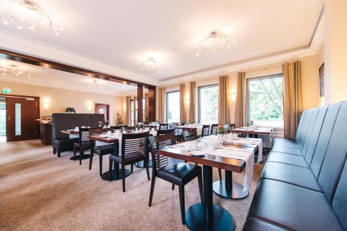 a dining room with tables and chairs and windows at HOTEL KOCKS am Mühlenberg in Mülheim an der Ruhr