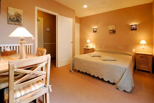 a bedroom with a bed and a table and lamps at Cit'Hotel des Messageries in Saintes