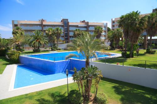 a large swimming pool with palm trees and a building at UHC Spa Aqquaria Family Complex in Salou