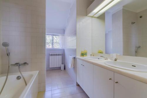 a bathroom with two sinks and a tub and a shower at House in Estoril in Estoril