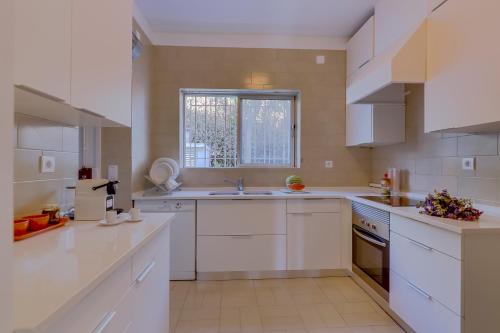 a white kitchen with a sink and a window at House in Estoril in Estoril
