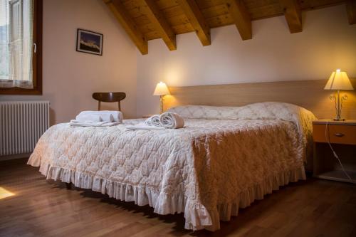 una camera con un letto e una sedia e due lampade di Albergo Diffuso Zoncolan a Ovaro