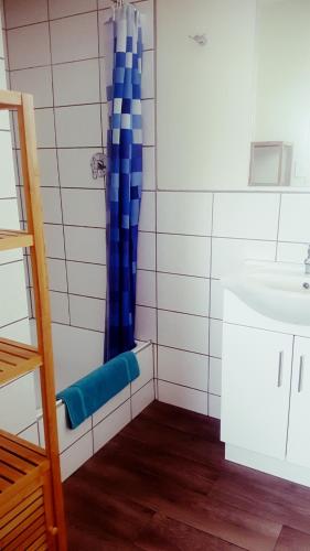 a bathroom with a blue shower curtain and a sink at Silver Wattle Cabins in Mount Morgan