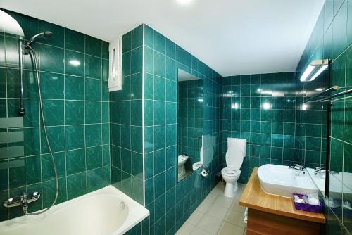 a green tiled bathroom with a tub and a sink at Hotel President in Timişoara