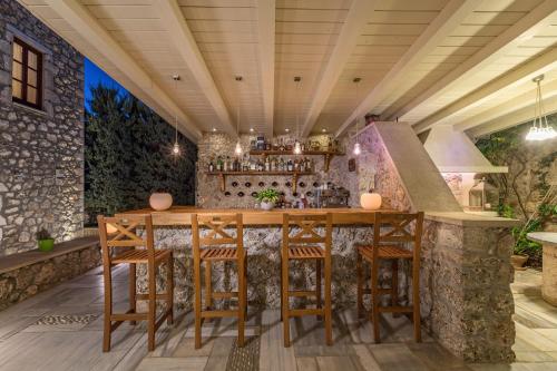 an outdoor kitchen with a bar with stools at Mare Monte Luxury Suites in Spetses