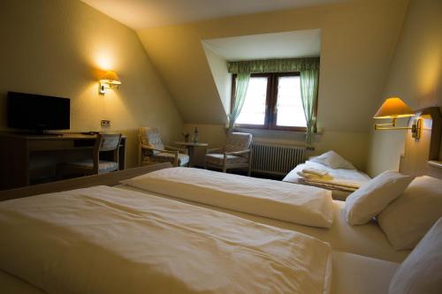 a hotel room with a large white bed and a desk at Landgasthof zum Lamm in Bahlingen