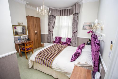 1 dormitorio con 1 cama grande con toques morados en Park Lodge Guest House, en Whitley Bay