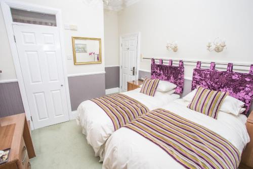 two beds in a bedroom with purple accents at Park Lodge Guest House in Whitley Bay