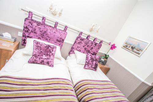 a bedroom with a large bed with purple pillows at Park Lodge Guest House in Whitley Bay
