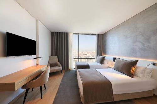 a hotel room with a bed and a desk and a tv at Iberostar Selection Lisboa in Lisbon