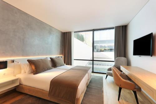 a hotel room with a bed and a desk and a television at Iberostar Selection Lisboa in Lisbon