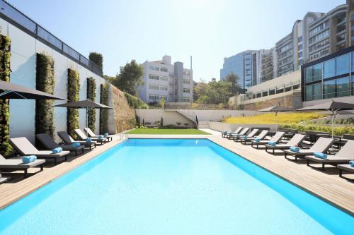 a swimming pool with lounge chairs and a building at Iberostar Selection Lisboa in Lisbon