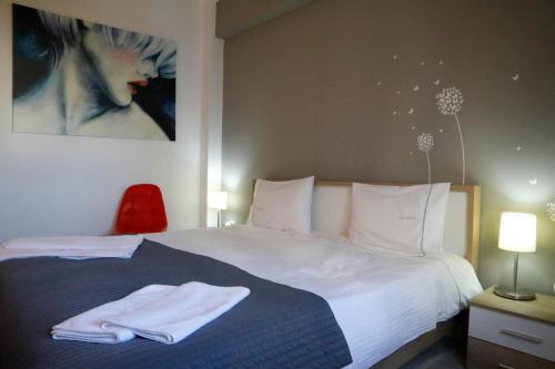 アテネにあるMetaxourghio Boutique Apartmentのベッドルーム1室(白いシーツと絵画付)