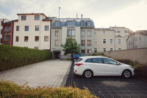a white car parked in a parking lot with buildings at apartmány Marco Shipping in České Budějovice