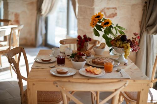 a wooden table with breakfast foods and flowers on it at Masseria Grieco in Ostuni