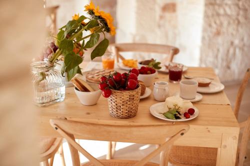 a wooden table with food and flowers on it at Masseria Grieco in Ostuni