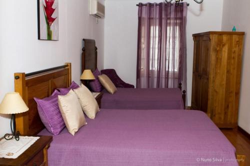 a bedroom with two beds with purple sheets and a table at Casa Do Brasao in Tabuaço