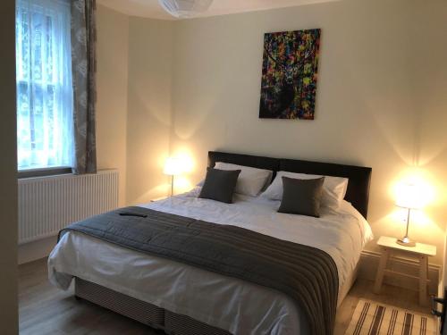 a bedroom with a large bed with two lamps at Good Intent Rooms in Waltham Abbey