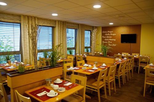 ein Restaurant mit Holztischen und -stühlen und einer Tafel in der Unterkunft Hotel Alberga in Mettmann