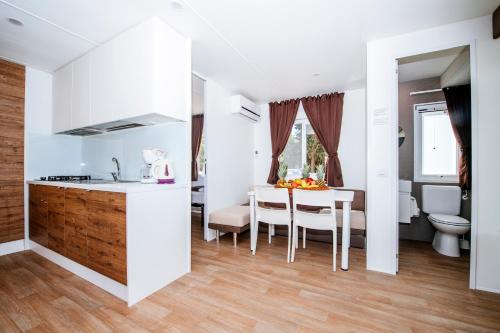 eine Küche und ein Esszimmer mit weißen Wänden und Holzböden in der Unterkunft Zaton Holiday Resort Mobile Homes in Nin