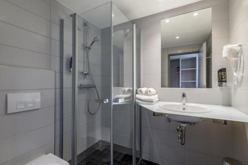 a bathroom with a shower and a sink and a mirror at Hotel Irschenberg Süd in Irschenberg