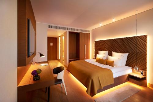 a hotel room with a large bed and a desk at BEYOND by Geisel - Adults only in Munich