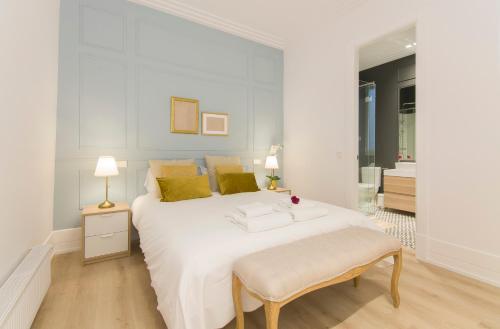 a white bedroom with a large white bed and a table at Luxury Alonso Martinez Madrid in Madrid