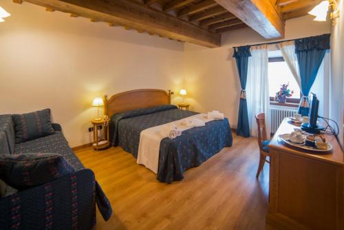 a bedroom with a bed and a couch and a chair at HG Abetone e Piramidi Resort in Abetone