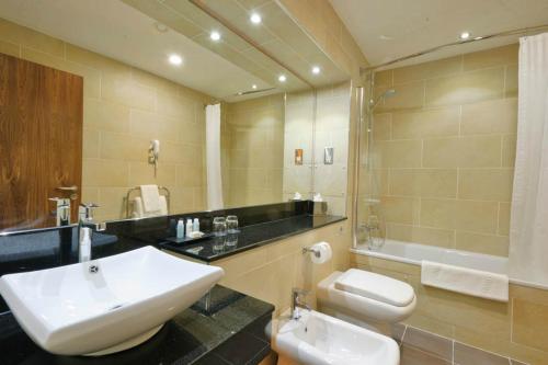a bathroom with a sink and a toilet and a mirror at Rox Hotel Aberdeen by Compass Hospitality in Aberdeen