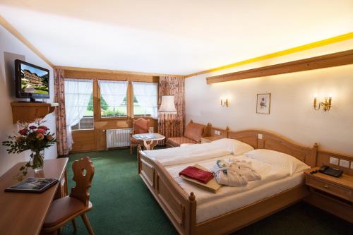 Habitación de hotel con cama y TV en Hotel Simmenhof, en Lenk