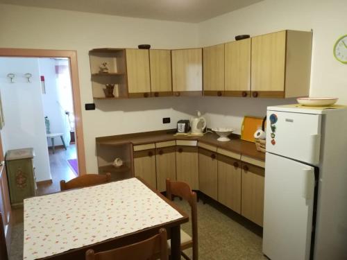 a kitchen with a table and a white refrigerator at appartamento di Bruno in Moena