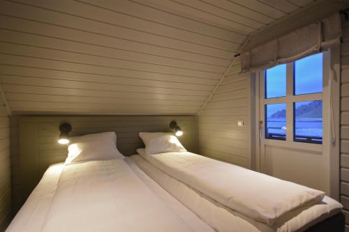 - 2 lits dans une petite chambre avec fenêtre dans l'établissement Bleik Sea Cabins, à Bleik