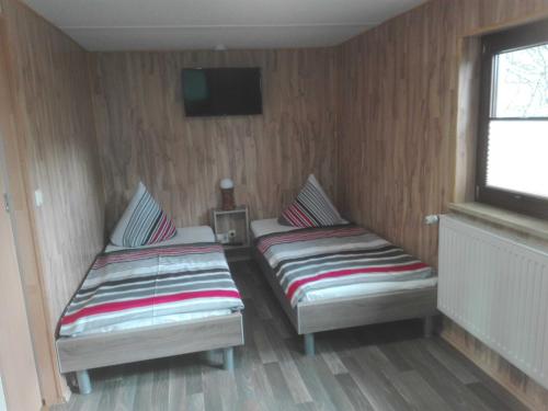 two beds in a room with a tv on the wall at Ferienbungalow 1 in Dierkow