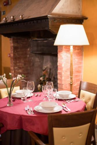 a table with a red table cloth with glasses and a lamp at HG Abetone e Piramidi Resort in Abetone