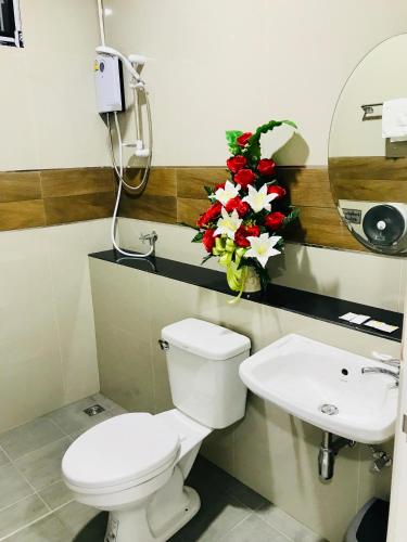 a bathroom with a toilet and a sink and flowers at Jarat Mansion in Surin