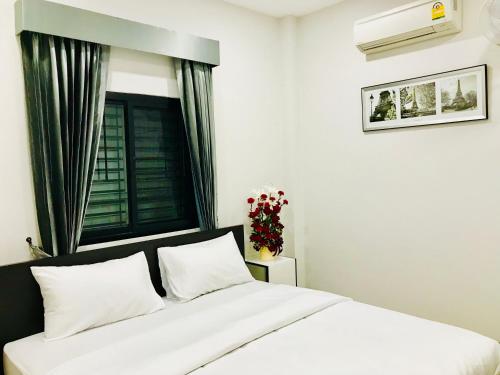 a bedroom with a white bed and a window at Jarat Mansion in Surin