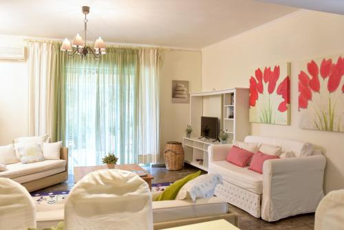 a living room with white furniture and pink pillows at Isabella Country House in Gouvia