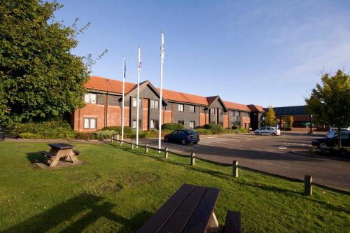 a park with a bench in front of a building at Days Inn Stevenage North in Baldock