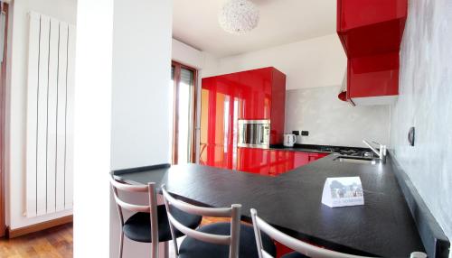 ミラノにあるItalianway-Rucellaiのキッチン(赤いキャビネット、黒いカウンタートップ付)